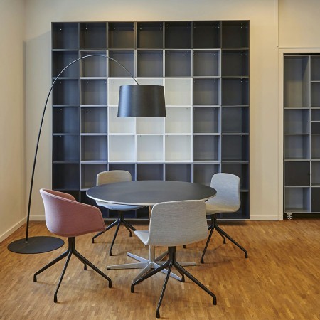 Büroraum mit rundem Tisch, vier Stühlen und großer Stehlampe