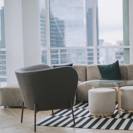 Helles Wohnzimmer mit Sofa, Sesseln, Couchtisch und gestreiftem Teppich auf Holzfußboden